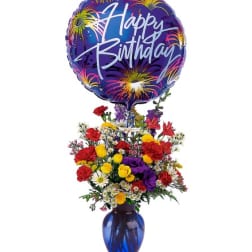 Birthday balloon above a colorful mixed flower arrangement in a blue vase
