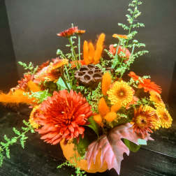 Orange and yellow chrysanthemum arrangement in a pumpkin container