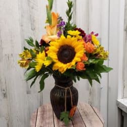 Sunflower and mixed flower arrangement in a dark vase