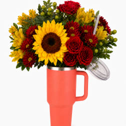 Bouquet of red and yellow flowers in a coral tumbler vase with lid and straw
