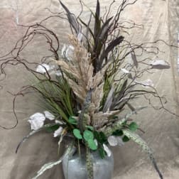 Tall arrangement of dried grasses and white accents in a gray vase