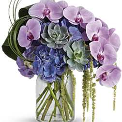 Bouquet of pink orchids and blue hydrangeas in a glass vase