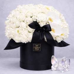 White roses and orchids in a black hat box with a black ribbon