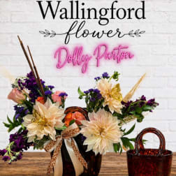Arrangement of cream and purple flowers in a tortoiseshell vase with ribbon