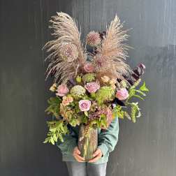 Tall bouquet of pink roses and dried grasses in a glass vase