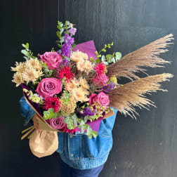 Large bouquet of pink roses, cream mums, and purple flowers with dried grasses
