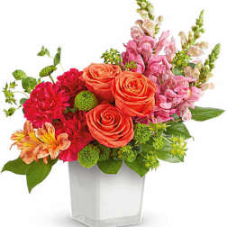 Mixed bouquet of orange roses, pink flowers, and green accents in a clear vase