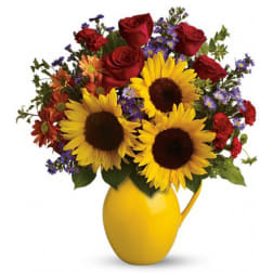 Bouquet of sunflowers, red roses, and purple flowers in a yellow pitcher vase