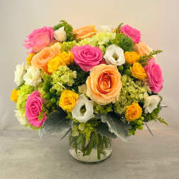 Bouquet of pink, peach, yellow, and white roses in a glass vase