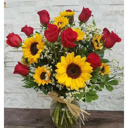 Bouquet of red roses and yellow sunflowers in a glass vase