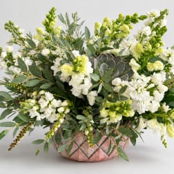 White and pale green floral arrangement in a pink textured vase