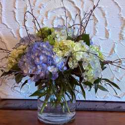 Blue and white hydrangea arrangement in a clear glass vase