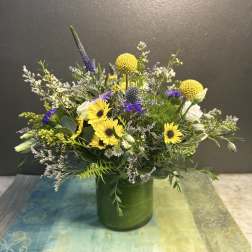 Mixed bouquet with yellow sunflowers and purple accents in a green vase