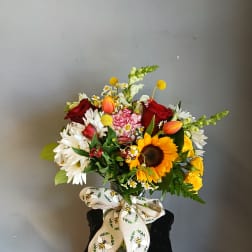 Mixed bouquet with sunflowers, roses, daisies, and tulips in a vase