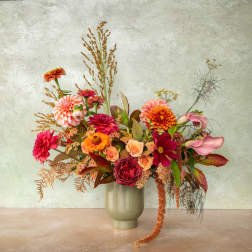 Colorful mixed bouquet in a pale vase with pink and orange blooms