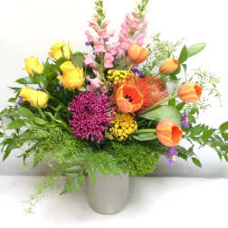 Mixed bouquet of yellow roses, orange tulips, and purple blooms in a vase