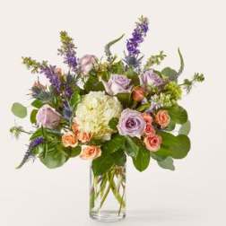 Lavender roses and purple flowers in a clear glass vase