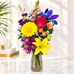 Colorful bouquet with roses, lilies, iris, and gerbera in a glass vase
