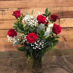 Red roses arranged in a clear glass vase with white baby's breath