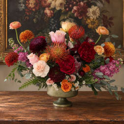 Mixed bouquet of red, pink, and orange flowers in a pedestal vase