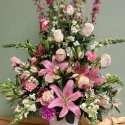 Pink lilies and roses arranged in a white vase
