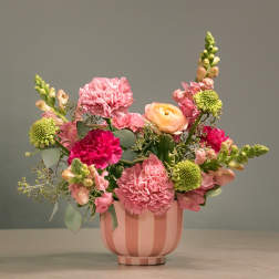 Pink and peach mixed flower arrangement in a striped pink vase