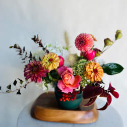 Mixed bouquet of pink, orange, and yellow flowers in a teal vase