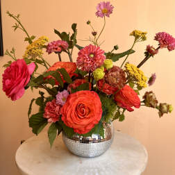 Bright mixed bouquet in a mirrored round vase