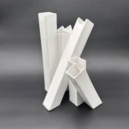 Four white ceramic vases with angular openings on a dark background