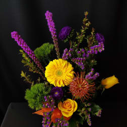 Yellow gerbera and roses with purple accents in a bouquet
