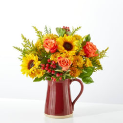 Sunflower and orange rose arrangement in a red ceramic pitcher