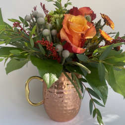 Orange rose bouquet in a copper mug vase