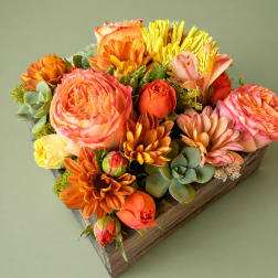 Orange and pink floral arrangement in a wooden box with succulents