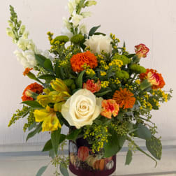 Mixed bouquet with white roses, yellow lilies, and orange flowers in a decorated vase