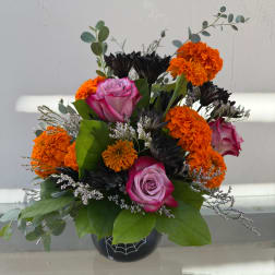 Pink roses and orange carnations in a black vase with spiderweb design
