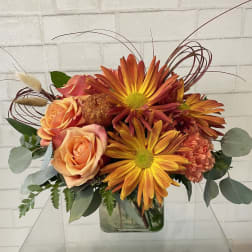 Orange and peach roses with yellow-orange chrysanthemums in a glass vase