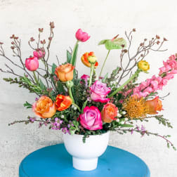 Mixed bouquet of roses, tulips, and snapdragons in a white vase