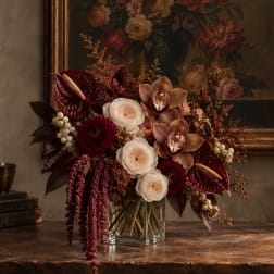 Dark burgundy and cream floral arrangement in a clear glass vase