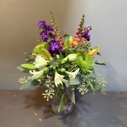 Colorful bouquet in a glass vase with purple, white, and green flowers