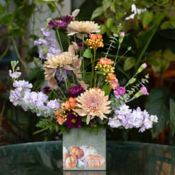 Mixed bouquet in a square vase with pastel and orange blooms