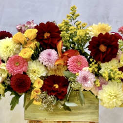 Mixed bouquet of red, pink, and yellow flowers in a wooden box