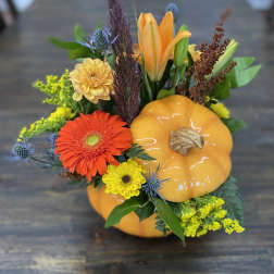 Fall floral arrangement with orange pumpkin decor and mixed blooms
