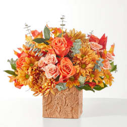Orange and peach flowers in a leaf-patterned square vase