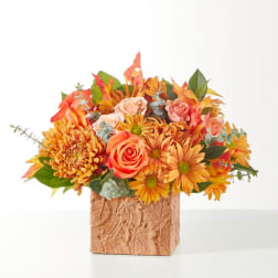 Autumn bouquet of orange and pink flowers in a textured square vase