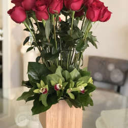 Tall arrangement of red roses with green orchids in a wooden box