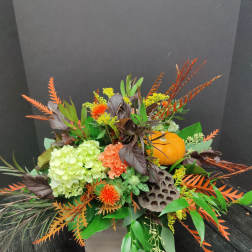 Autumn floral arrangement with hydrangea, orange blooms, and a small pumpkin in a box