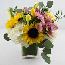 Bouquet of sunflowers, pink orchids, and white hydrangeas in a glass vase