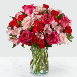 Pink and red mixed flower bouquet in a clear glass vase