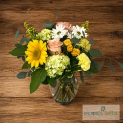 Mixed bouquet in a clear glass vase with yellow, white, and blush flowers