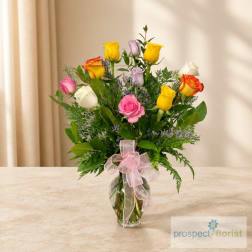 Mixed roses in a glass vase with a pink ribbon